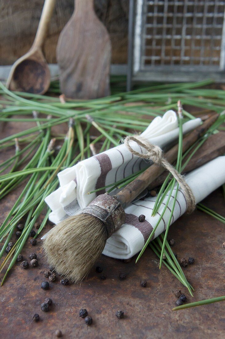 A brush, pine needles and peppercorns in a napkin