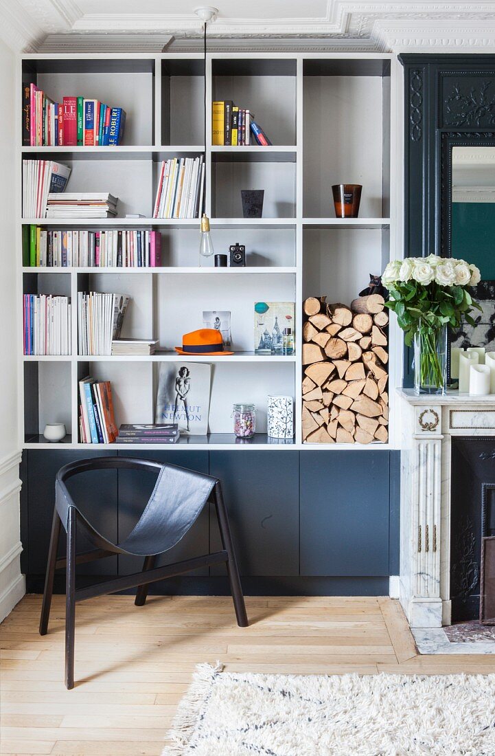 Fitted shelves and black designer chair next to fireplace