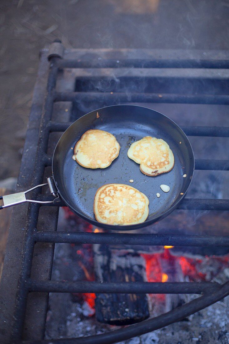 Pancakes in Pfanne auf Feuerrost