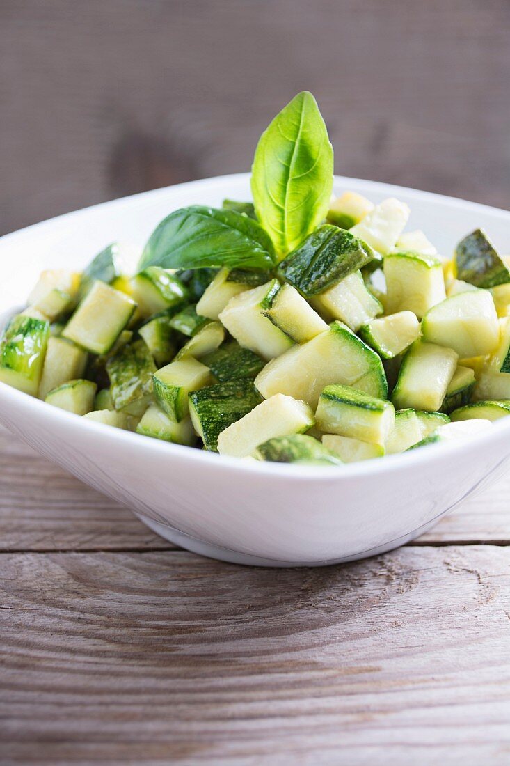 Diced zucchini in a bowl on a wood table