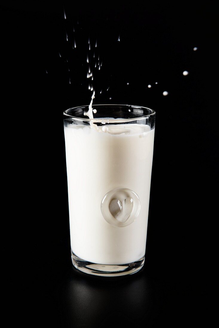 Glas Milch mit Splash auf schwarzem Hintergrund
