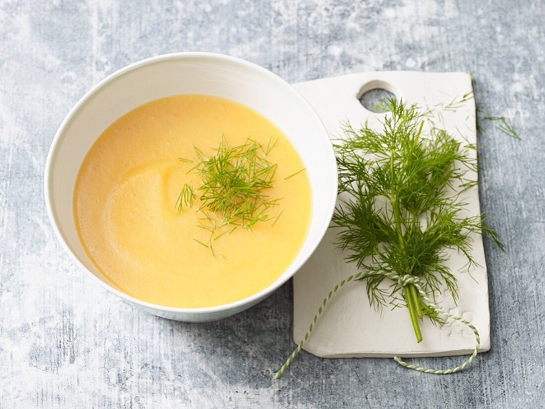 A bowl of potato and carrot soup with fresh dill