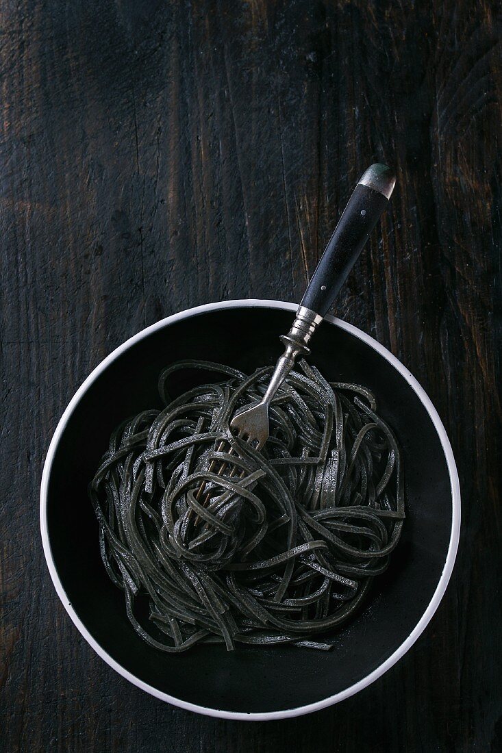 Cooked black cuttlefish ink spaghetti over black background. View from above