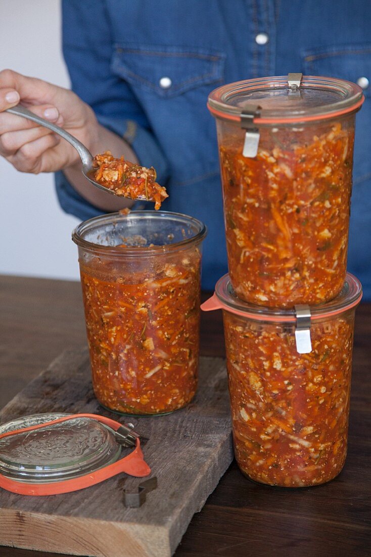 Vegan vegetable bolognese being put into glass storage jars