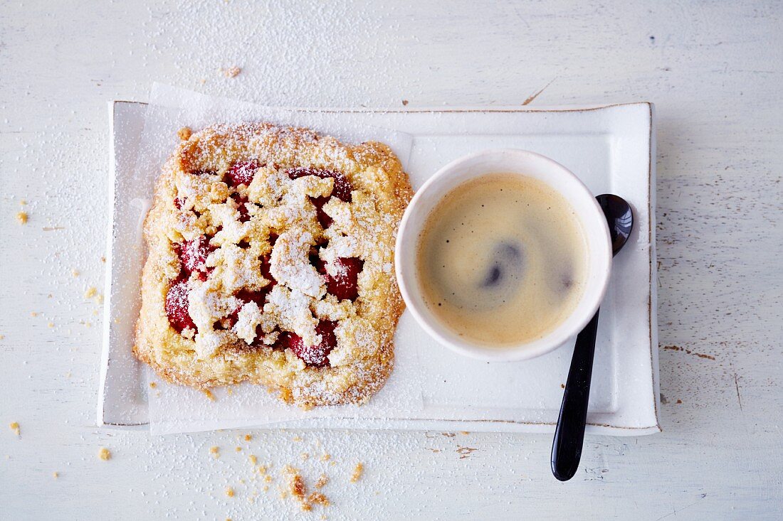A vegan raspberry crumble slice (soya-free) served with a cup of coffee