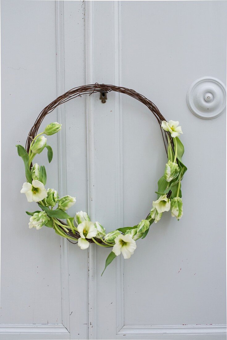 Rustic wreath made from rusty wire and tulips on cupboard door