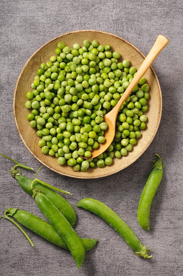 Peas in a wooden bowl with a spoon