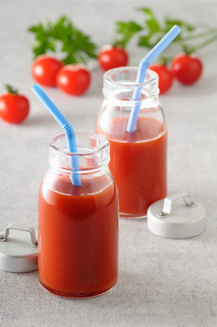 Zwei Flaschen Tomatensaft mit Strohhalmen