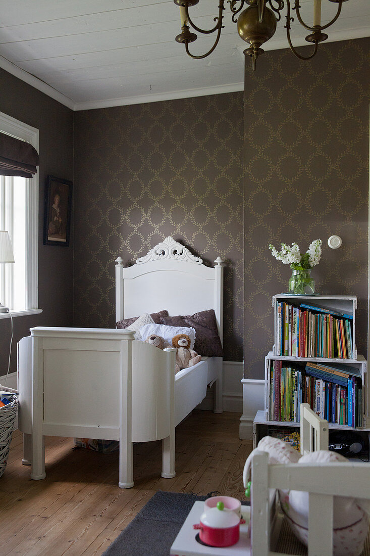 Old bed in child's bedroom with brown wallpaper