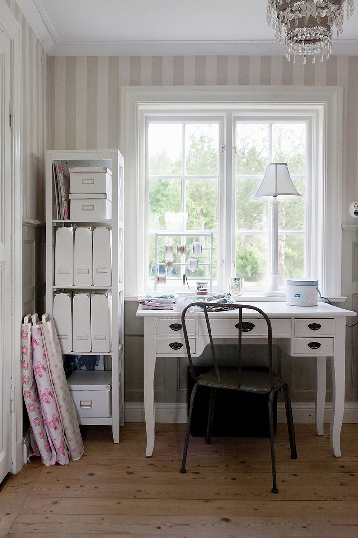 Desk below window in room with striped wallpaper