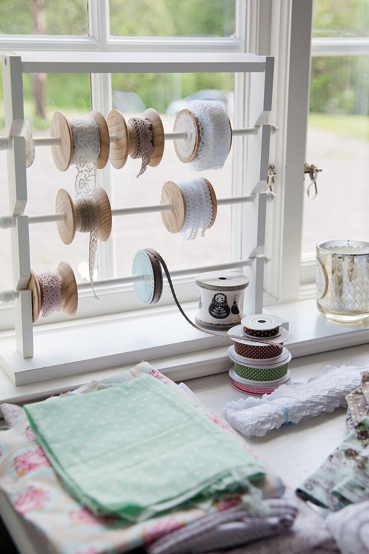 Reels of pretty ribbons on frame in window