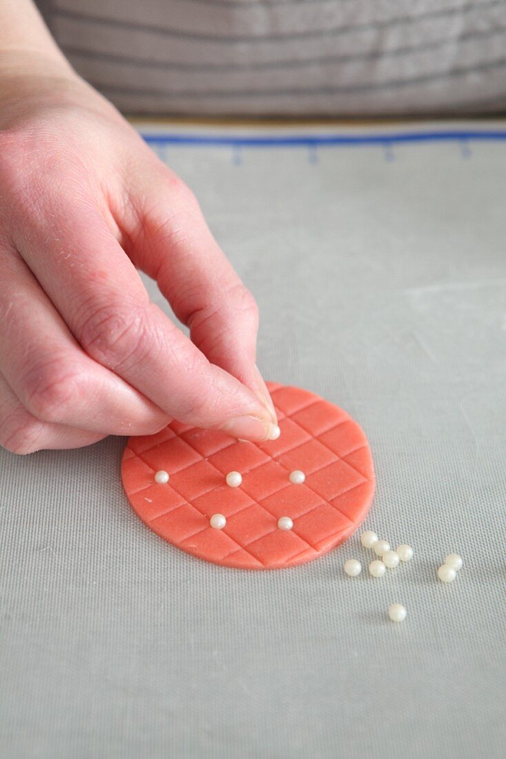 Sugar pearls being applied to a quilted pattern cake decoration