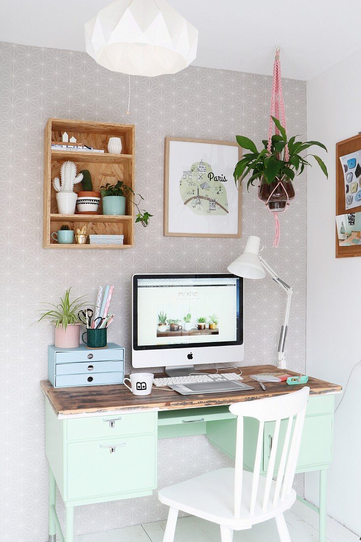 Monitor on mint-green retro desk and white wooden chair in corner
