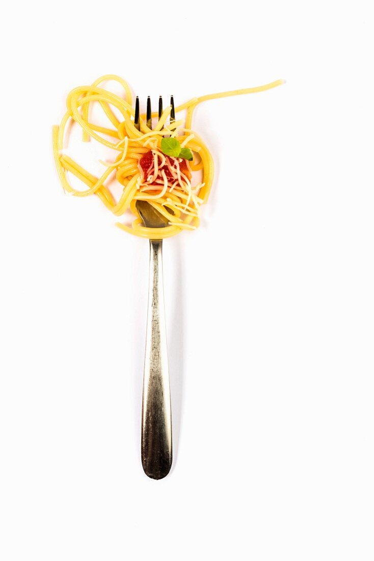 Spaghetti mit Tomaten und Basilikum auf Gabel (Draufsicht)