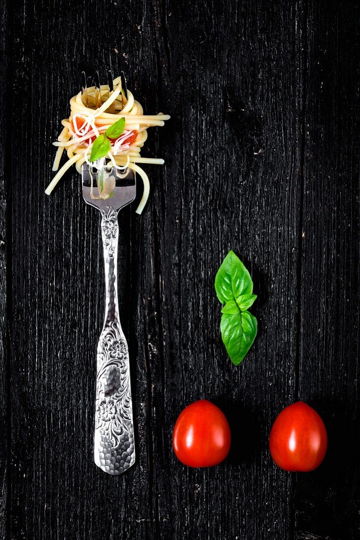 Italian pasta with tomato and basil on fork On wooden board
