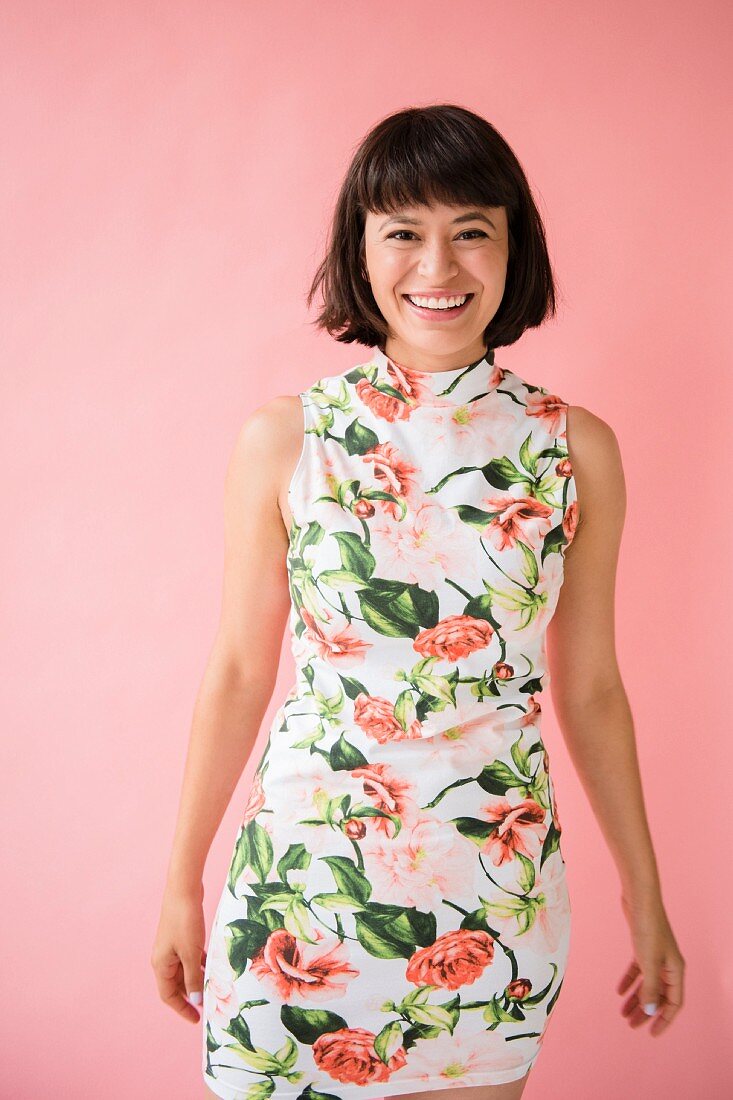 A young brunette woman wearing a short floral dress