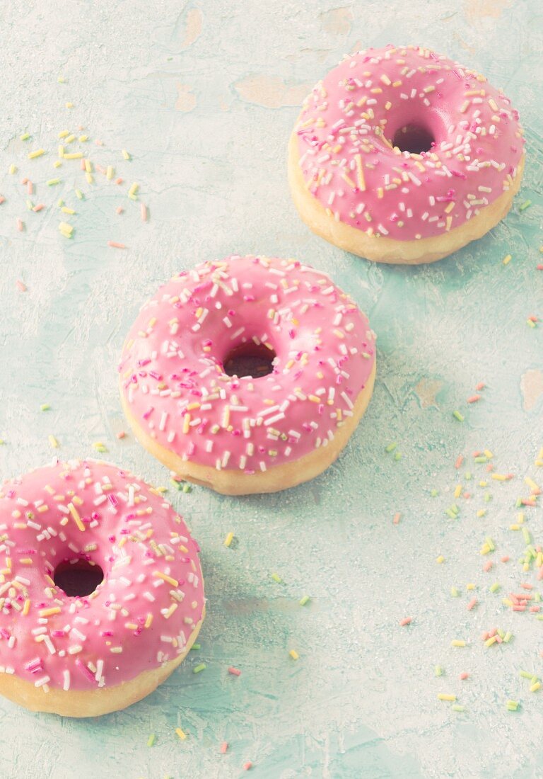Three pink donuts with sugar sprinkles