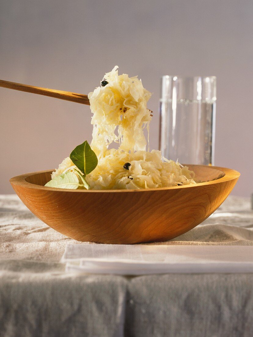 Sauerkraut mit Wacholderbeeren auf Holzgabel über Holzschale