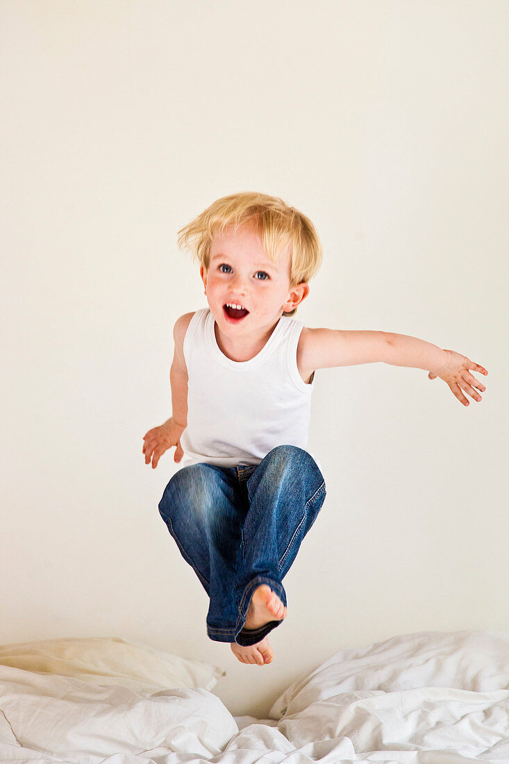 Boy jumping on bed