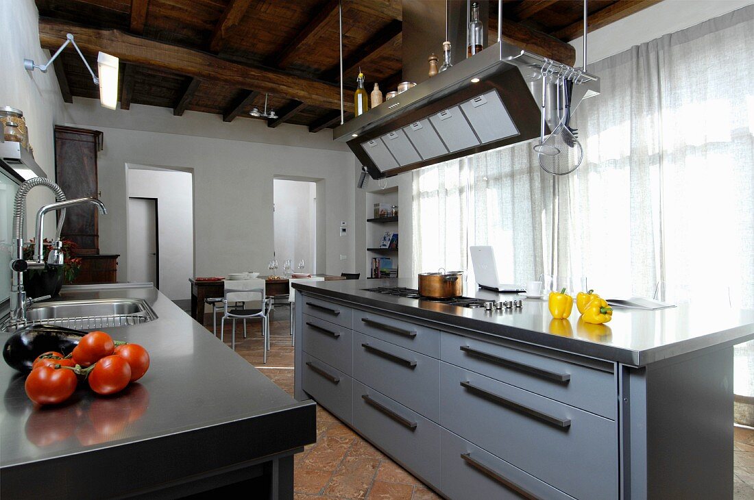Moderne Kücheninsel in renoviertem Landhaus mit rustikaler Holzbalkendecke