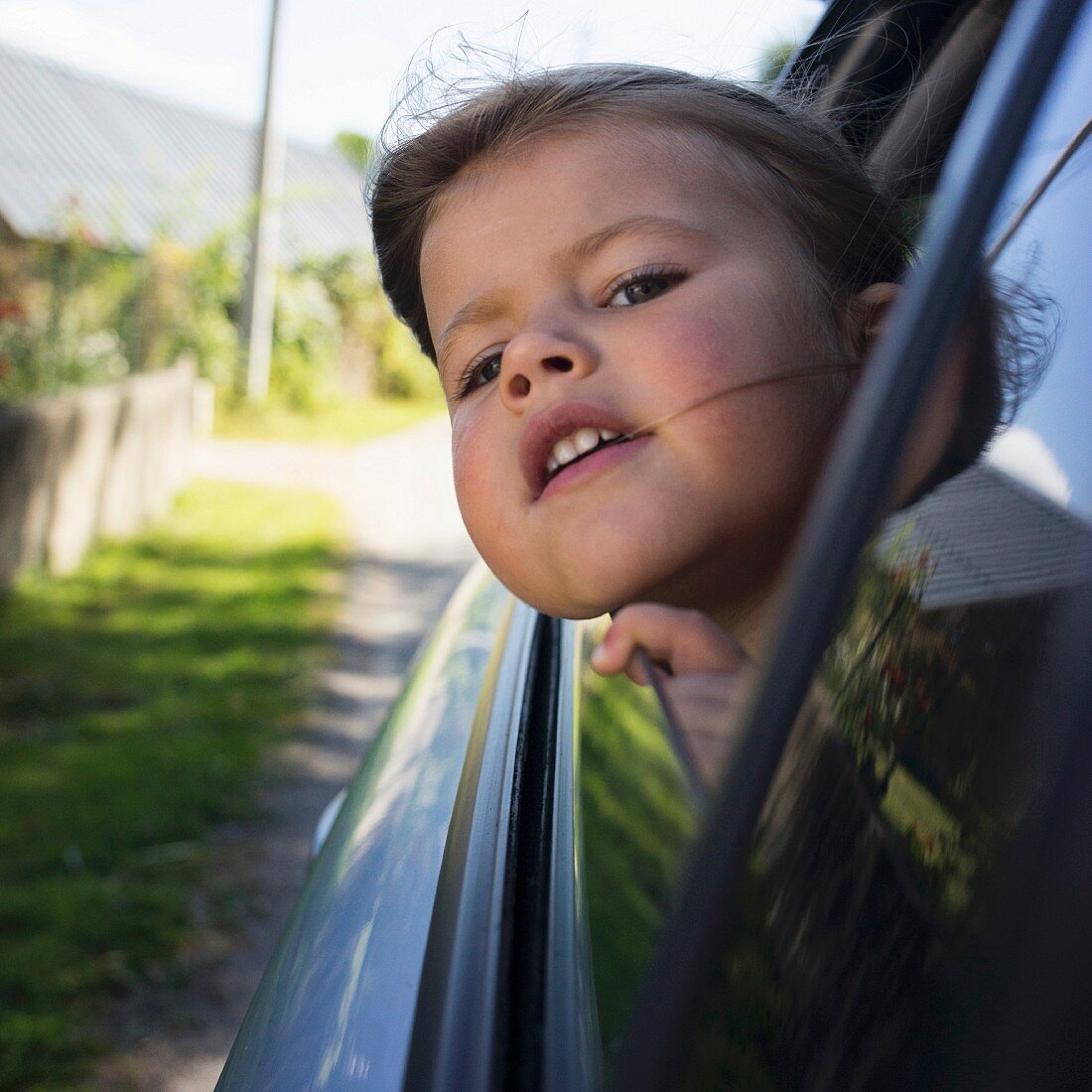 A little girl with her head out of a car window