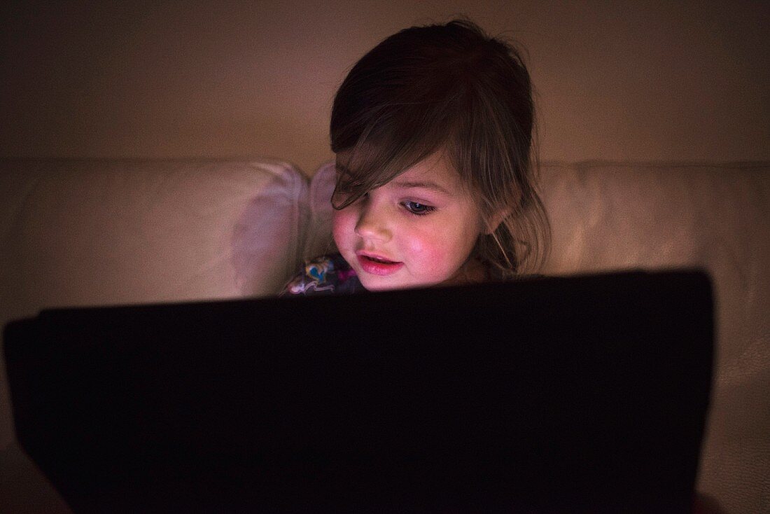 A little girl in the light of a screen