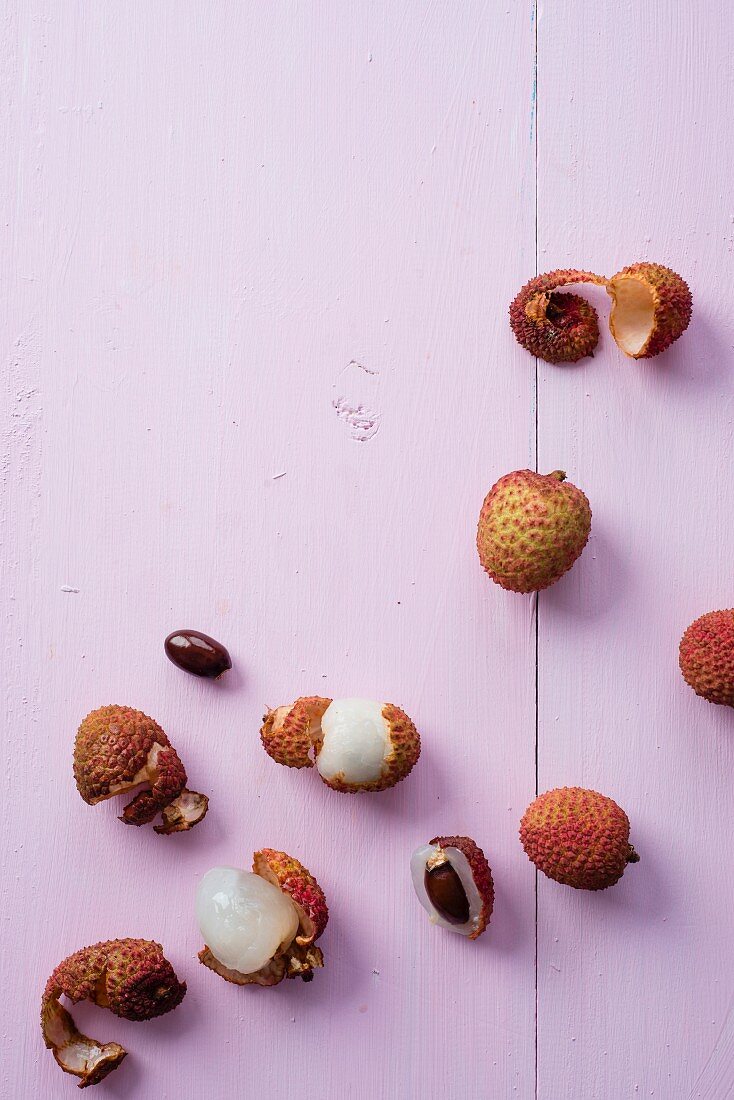 Lychees, lychee shells and stones on a purple surface