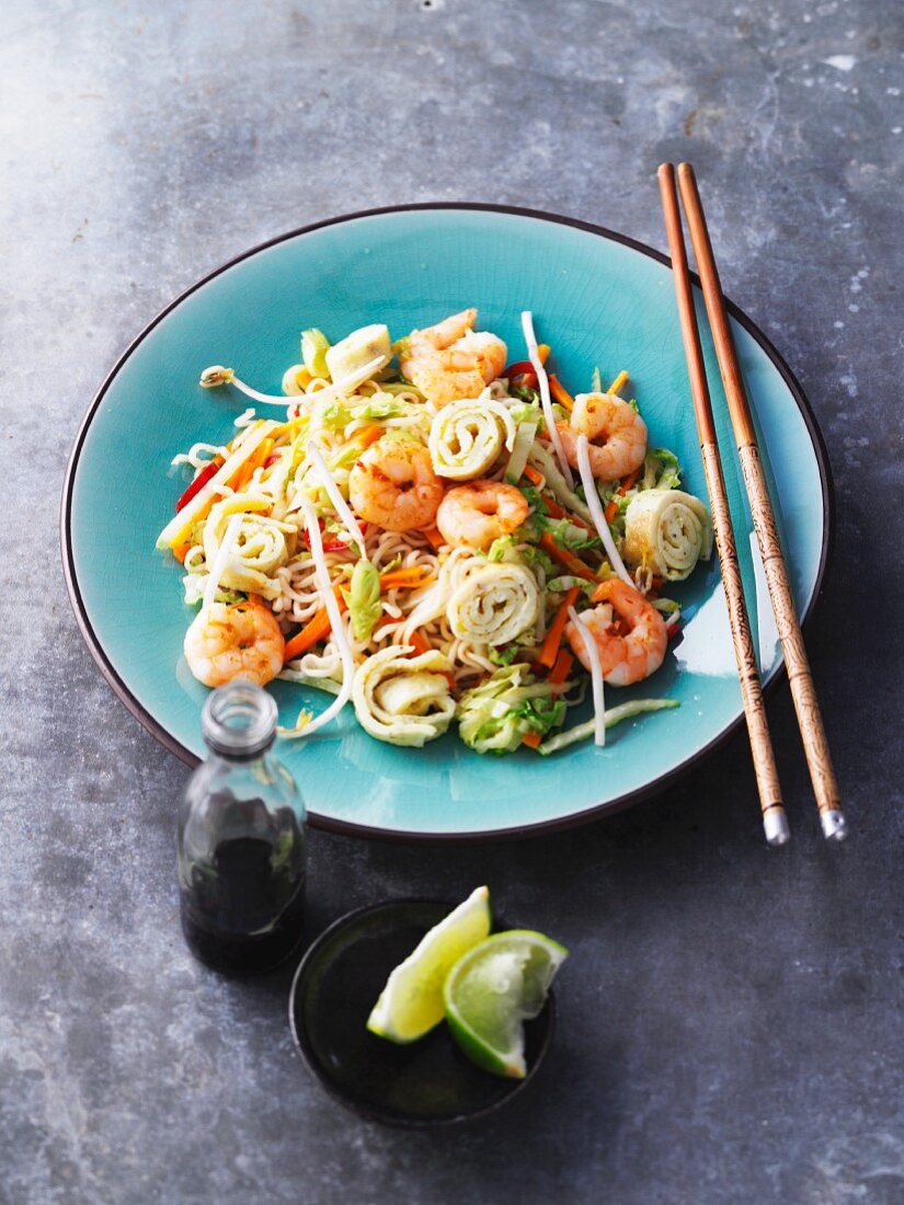 Fried oriental noodles with vegetables, prawns and on roles (Asia)