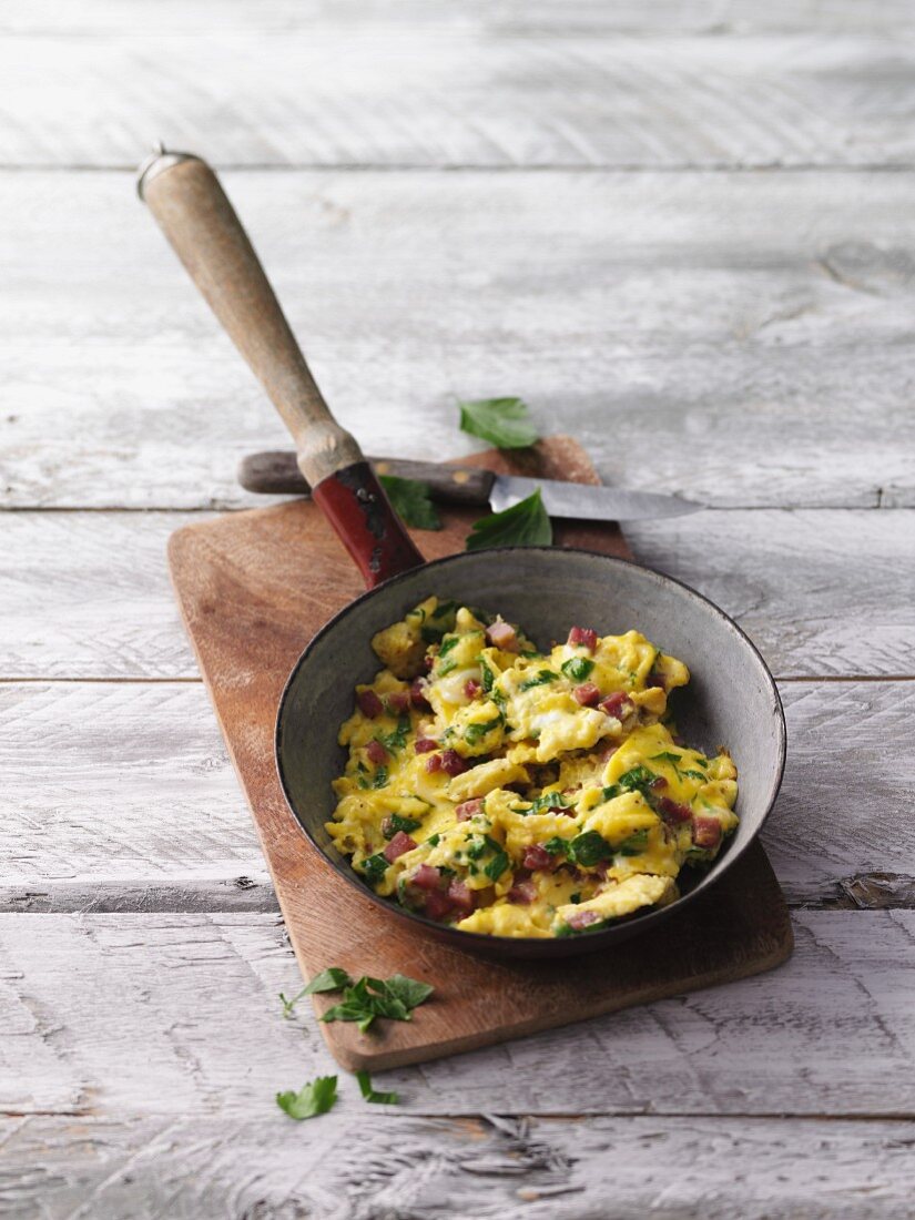 Herb scrambled egg with diced bacon in a pan