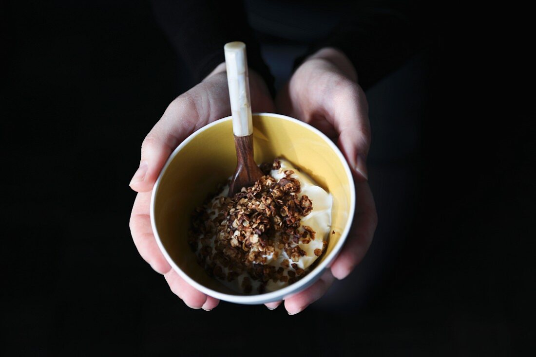 Hände halten Müsli mit Joghurt