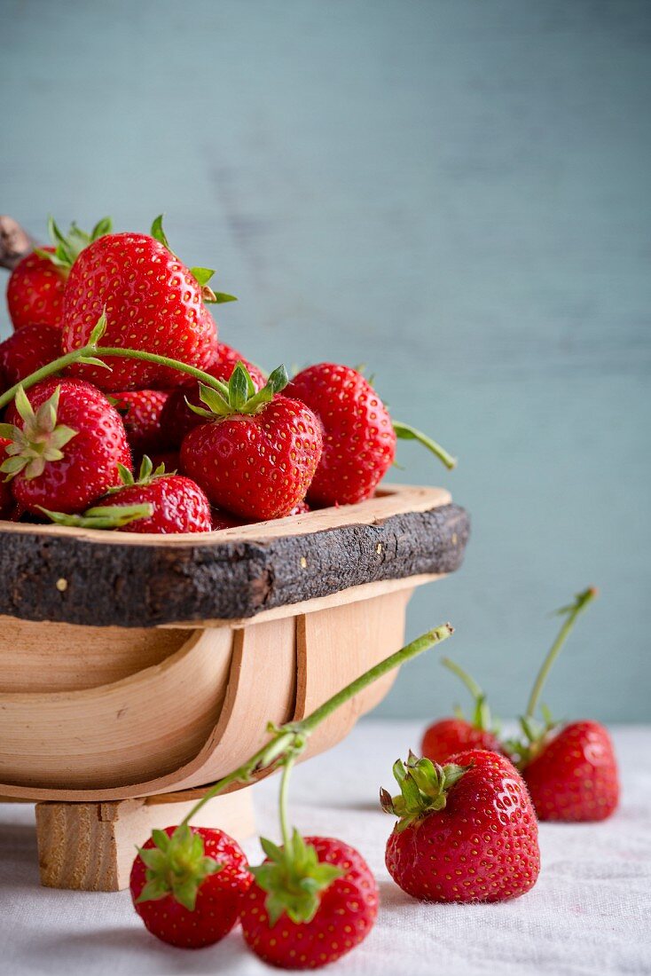 Strawberries in a wooden basket and on a white tablecloth