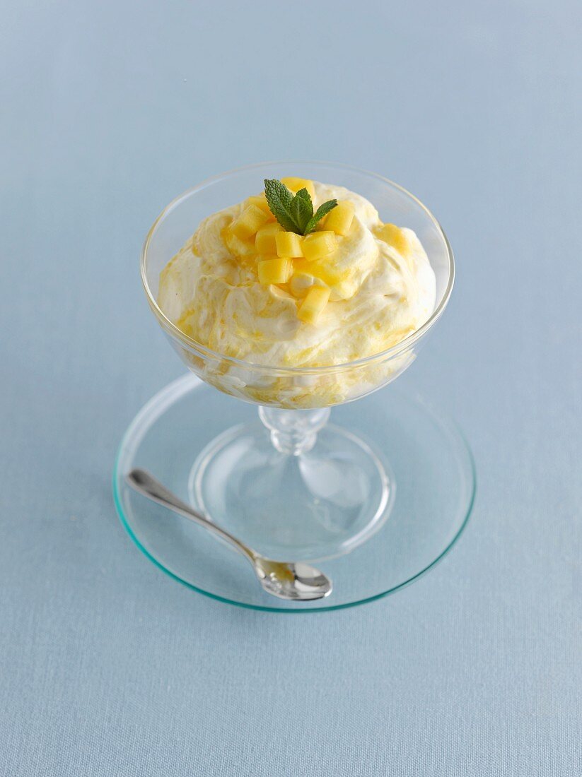 A mango fool in a glass bowl on a blue surface