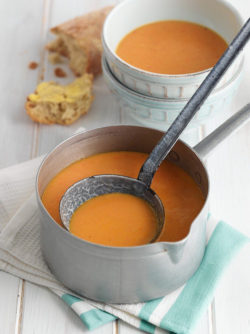 Tomato and mascarpone soup in a pan with soup bowls
