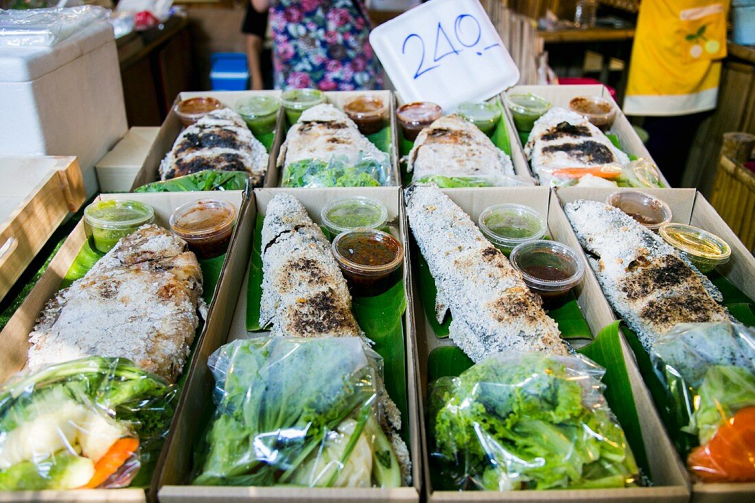 Fisch in der Salzkruste mit Salat und Sauce auf einem Markt in Thailand
