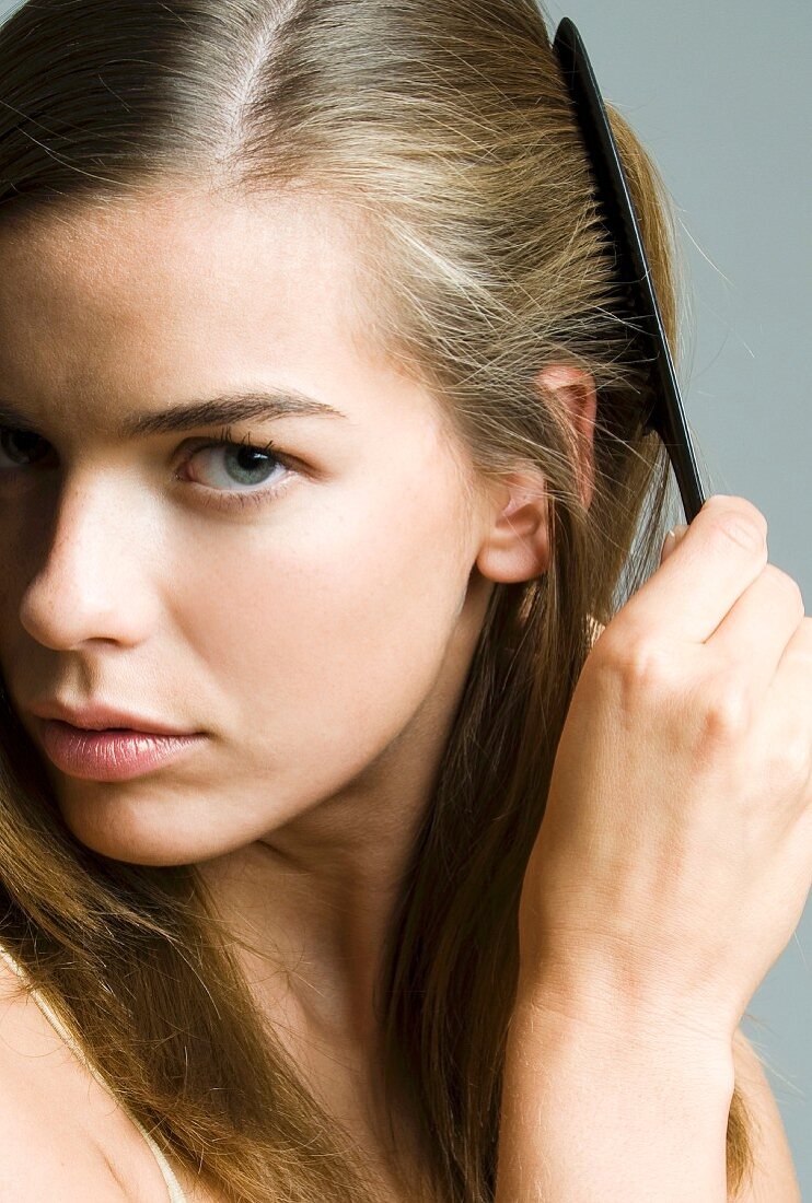 A dark blonde woman combing her hair