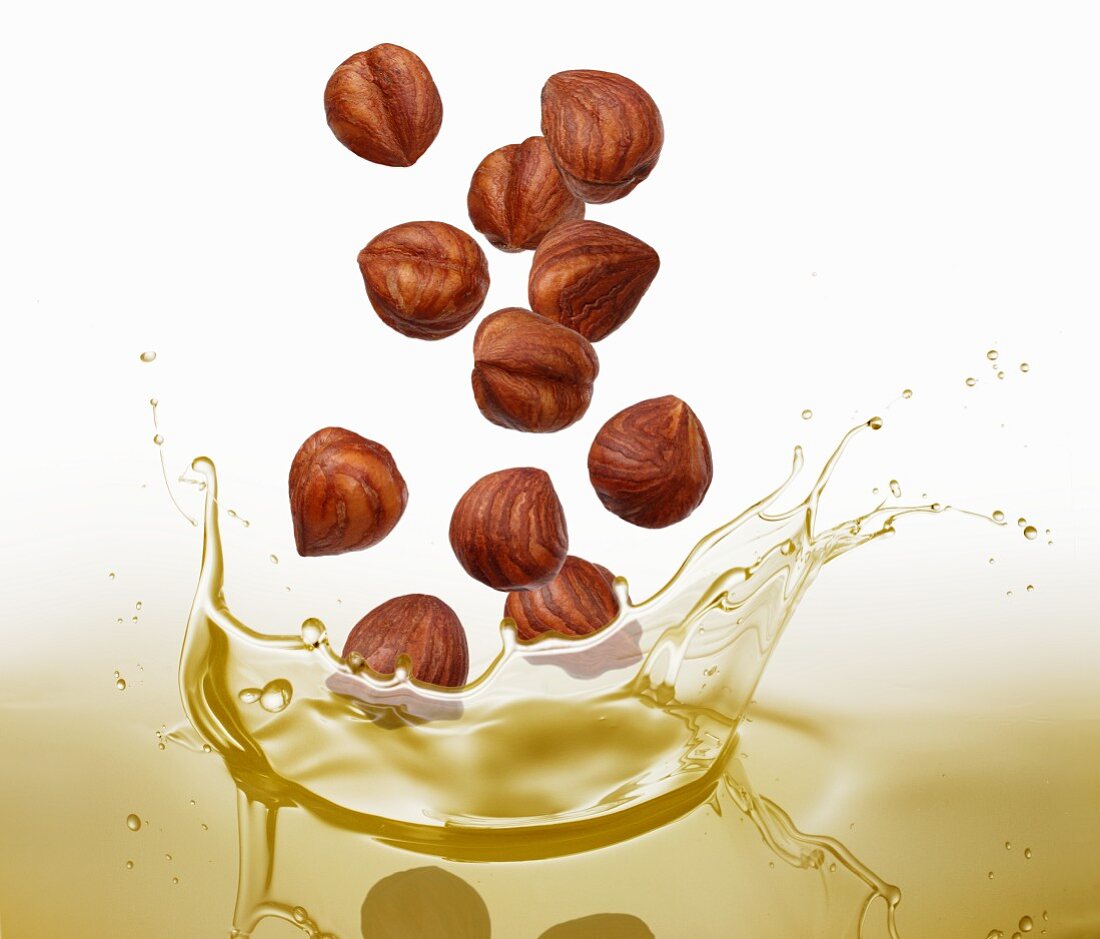 Hazelnuts falling into oil