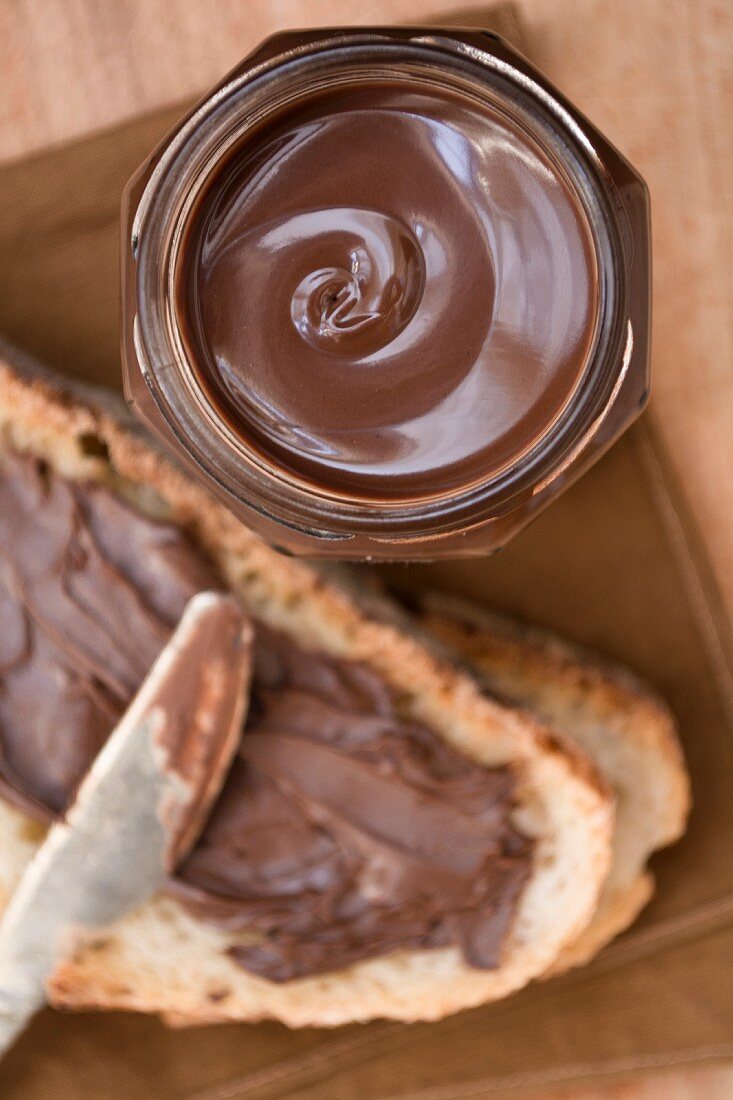 Schokoladenaufstrich im Glas und auf Brot