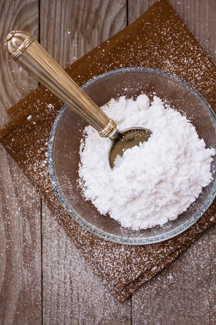 Icing sugar in a glass bowl with a vintage spoon