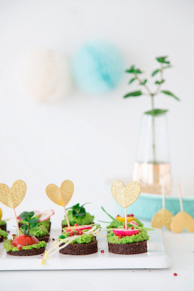 Pumpernickeltaler mit veganer Erbsen-Minzecreme dekoriert mit Herzsteckern