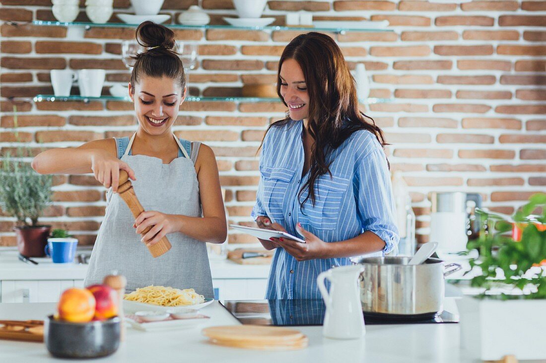 Two young women cooking pasta in a kitchen