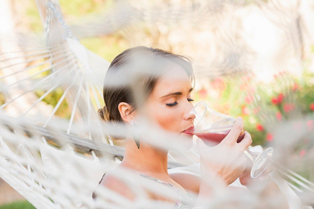 A woman in a hammock drinking a cocktail