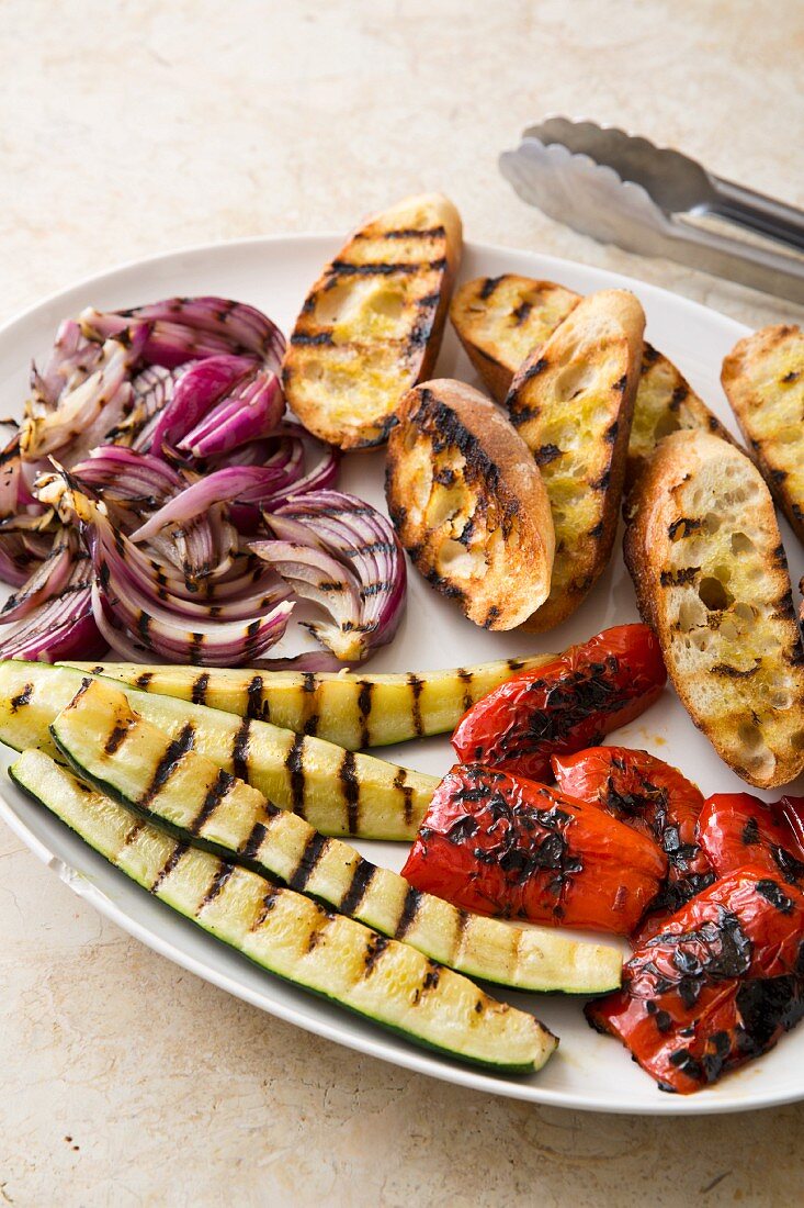 Ingredients for grilled panzanella (bread salad): grilled courgettes, red onions, peppers and grilled bread