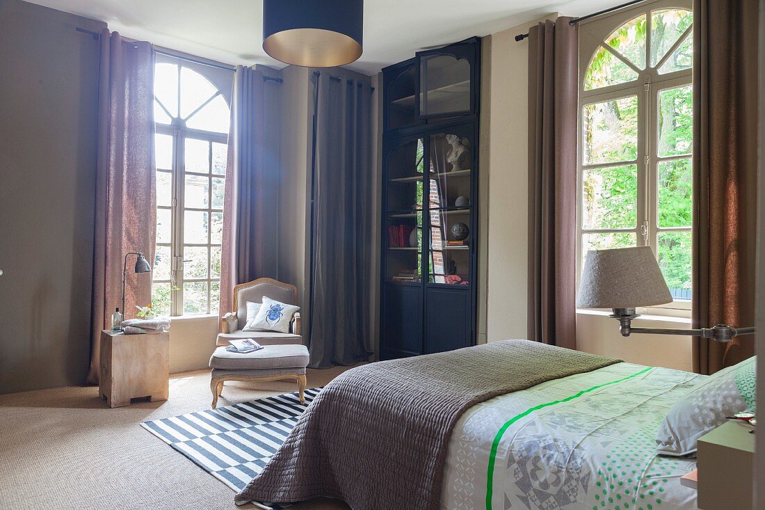 Elegantes Schlafzimmer mit Bogenfenstern und Barocksessel