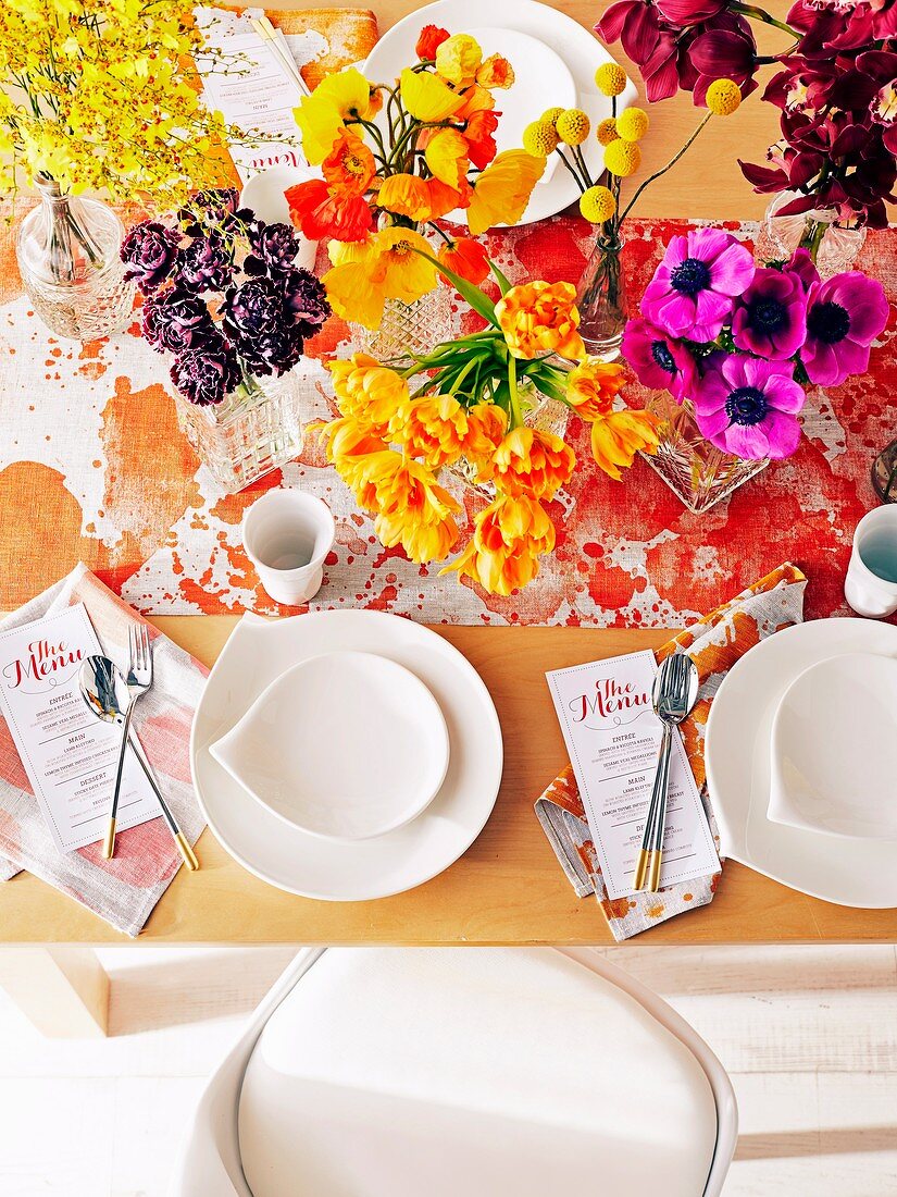 Bunte Tischdekoration mit Blumen und weißem Geschirr