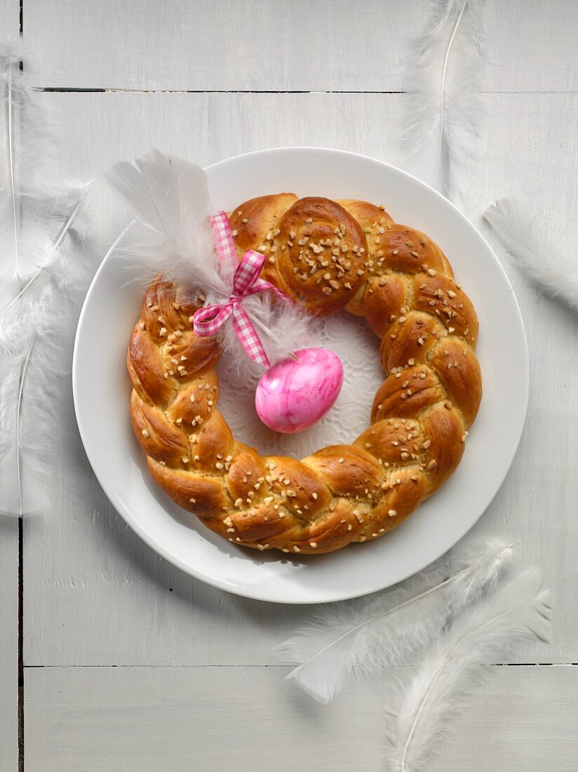 An Easter wreath with a pink Easter egg and a white feather