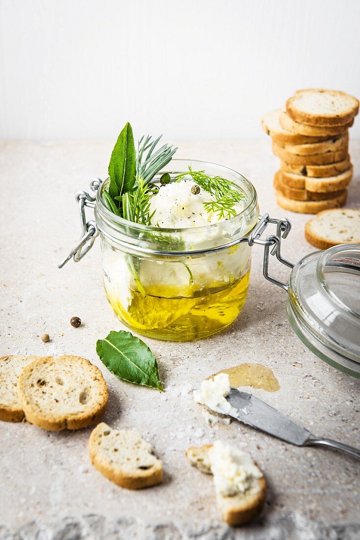 Selbstgemachter Ricotta in Olivenöl mit frischen Kräutern und Brotchips