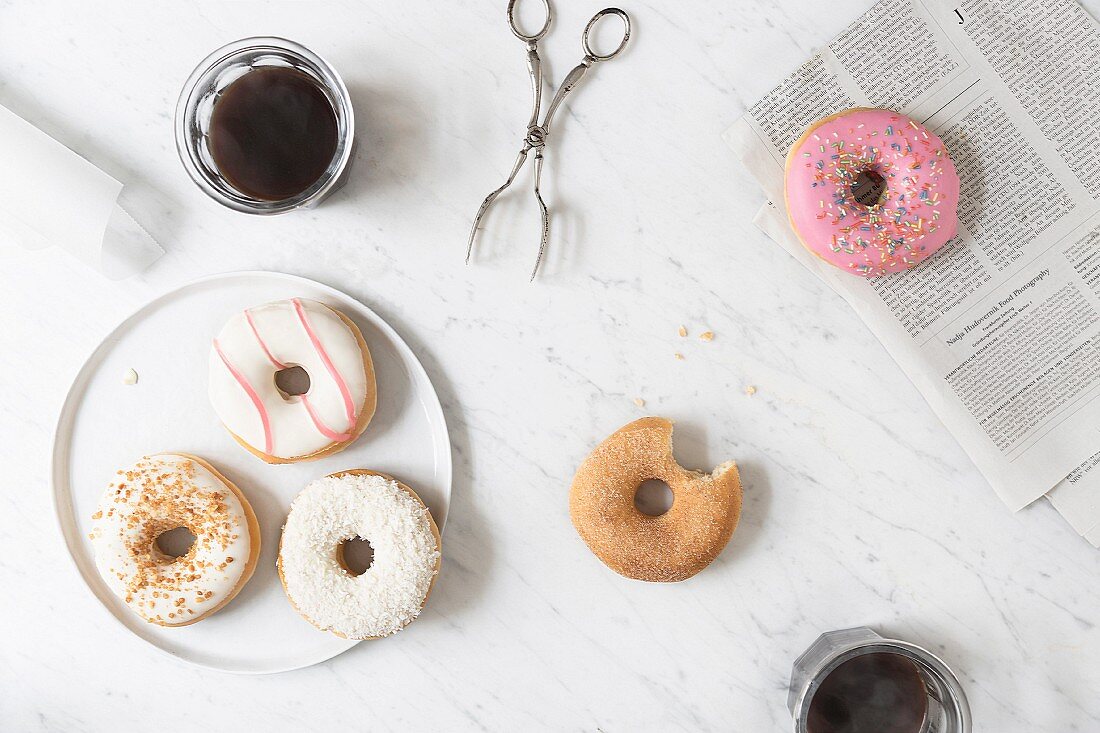 Iced doughnuts and a cinnamon-sugar doughnut with a bite taken out on a marble table