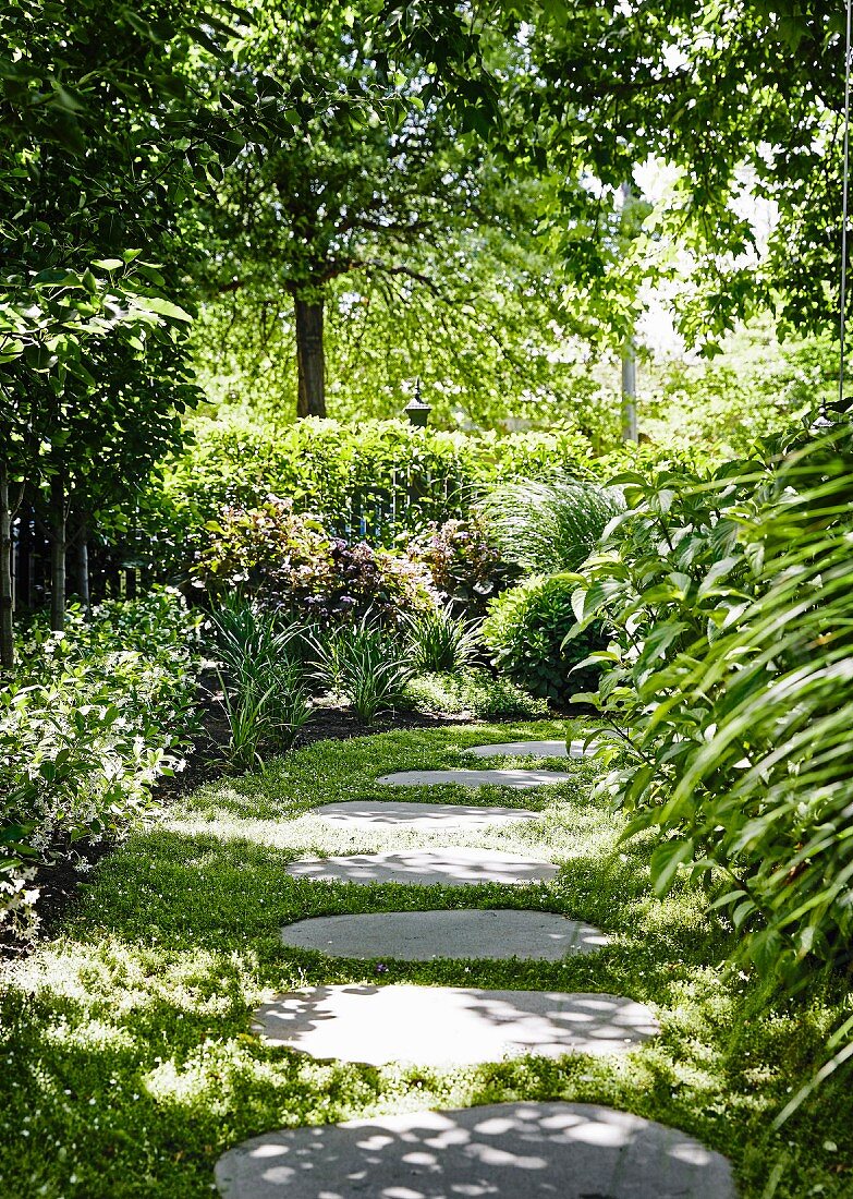 Garden path made of ingrown tread plates in the partially shaded garden