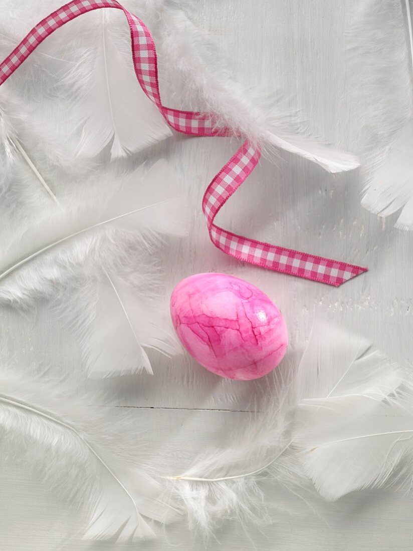 A coloured egg with a ribbon and feathers