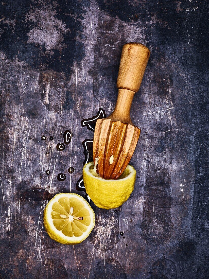 A halved lemon and a juicer on a metal surface